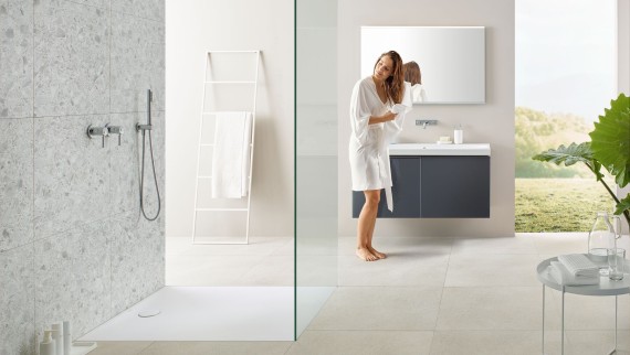 Woman drying her hair with a towel in a bathroom with open shower and large tiles in terrazzo style Woman drying her hair with a towel in a bathroom with open shower and large tiles in terrazzo style