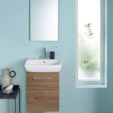 A wall-hung Renova Plan WC and a washbasin area attached to a light blue wall A wall-hung Renova Plan WC and a washbasin area attached to a light blue wall