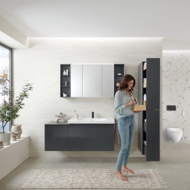 Woman opens tall cabinet with lots of storage space in bathroom with Geberit Acanto bathroom furniture Woman opens tall cabinet with lots of storage space in bathroom with Geberit Acanto bathroom furniture