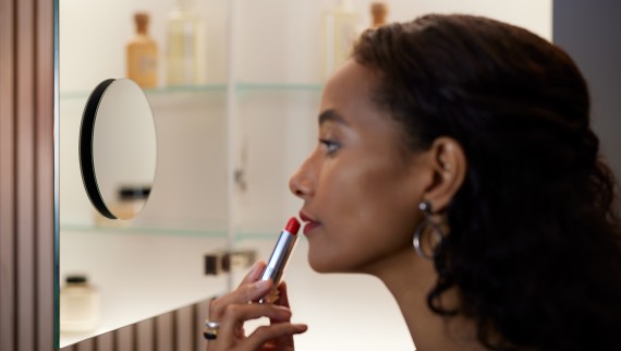 Woman applying lipstick in front of a magnifying mirror (© Geberit) Woman applying lipstick in front of a magnifying mirror (© Geberit)