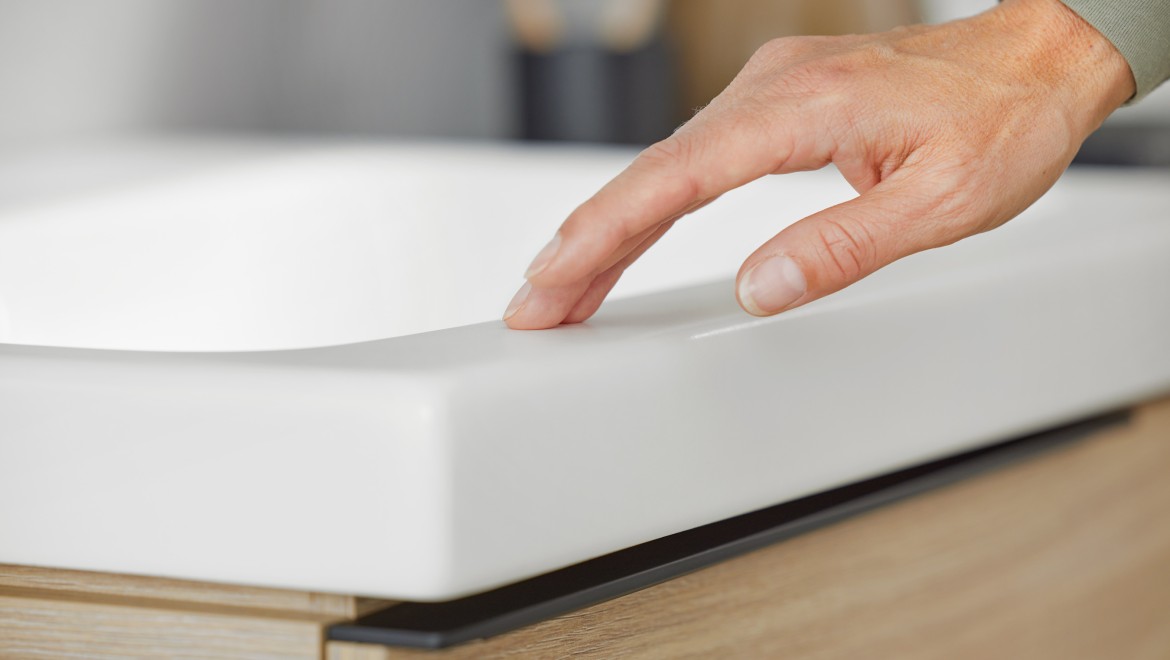 Macro image of a hand touching a Geberit iCon washbasin in white matt Macro image of a hand touching a Geberit iCon washbasin in white matt